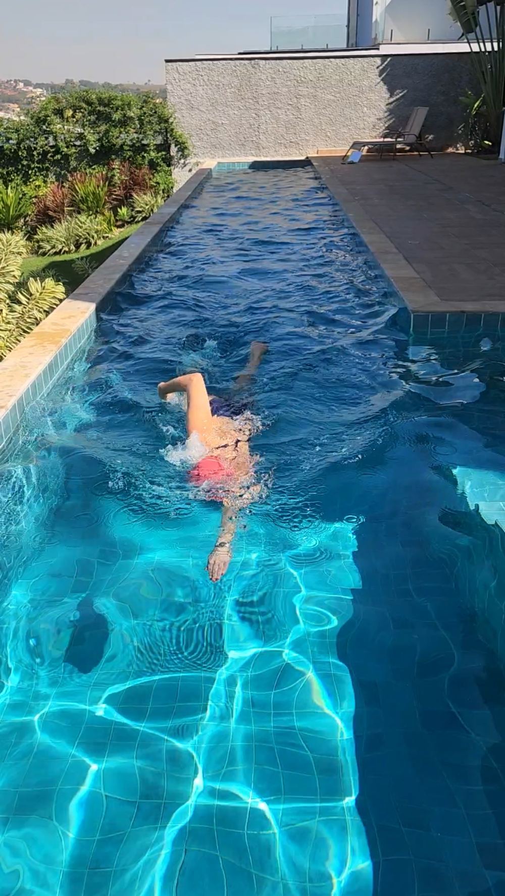 Pessoa nadando em piscina aquecida por bomba de calor instalada pela Renew Energia